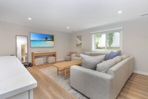 A modern living room with a sofa, coffee table, and a TV displaying a beach scene.