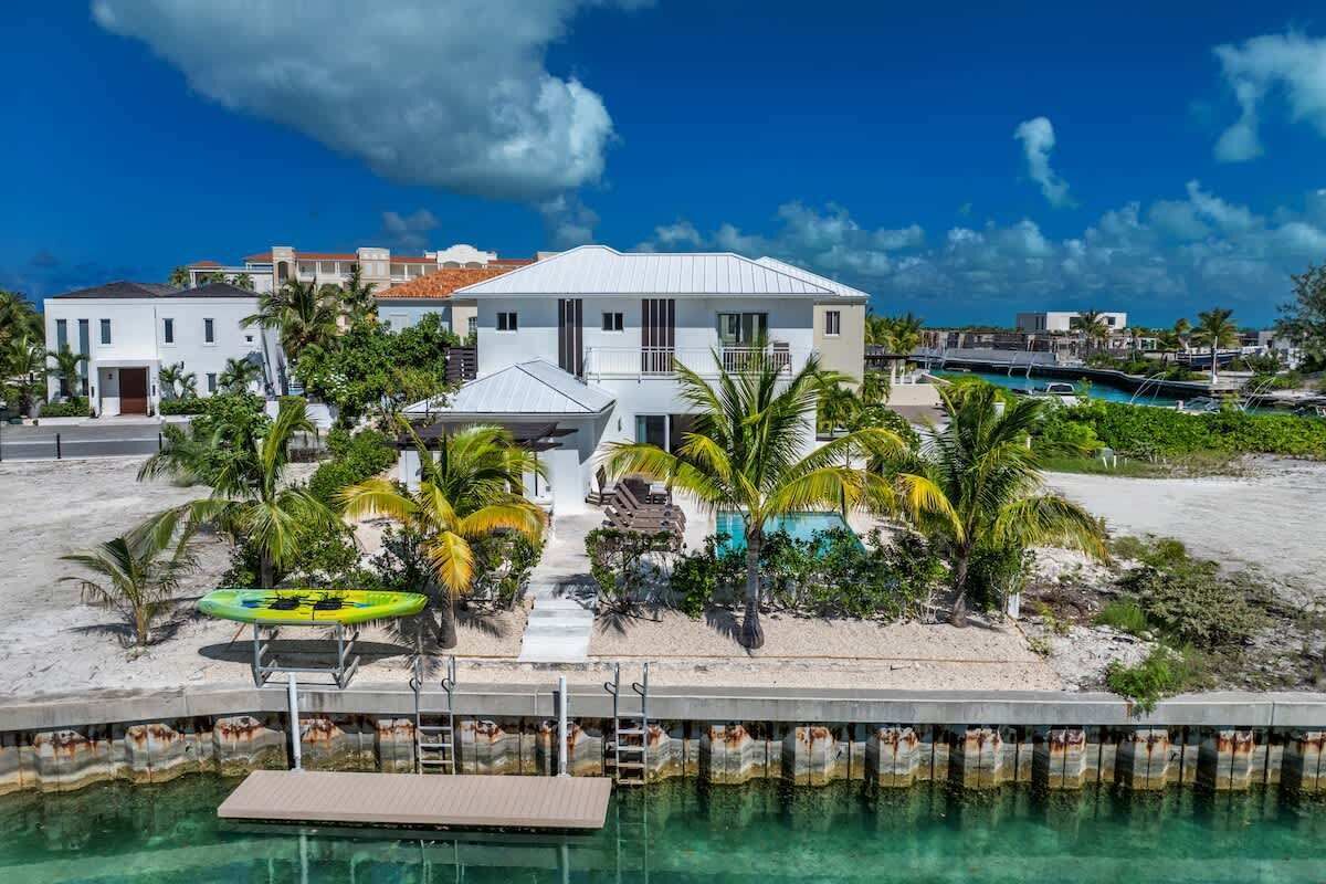 Une propriété située en bord de mer, dotée d’une piscine, de palmiers et d’un quai.