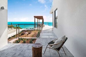 Ein Balkon mit Meerblick, einem Holztisch und einem Stuhl mit Kissen.
