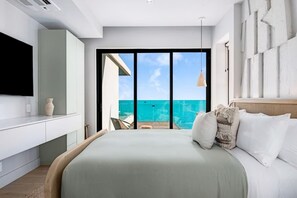 Ein modernes Schlafzimmer mit einem großen Bett, einem Flachbildfernseher und einem Balkon mit Meerblick.