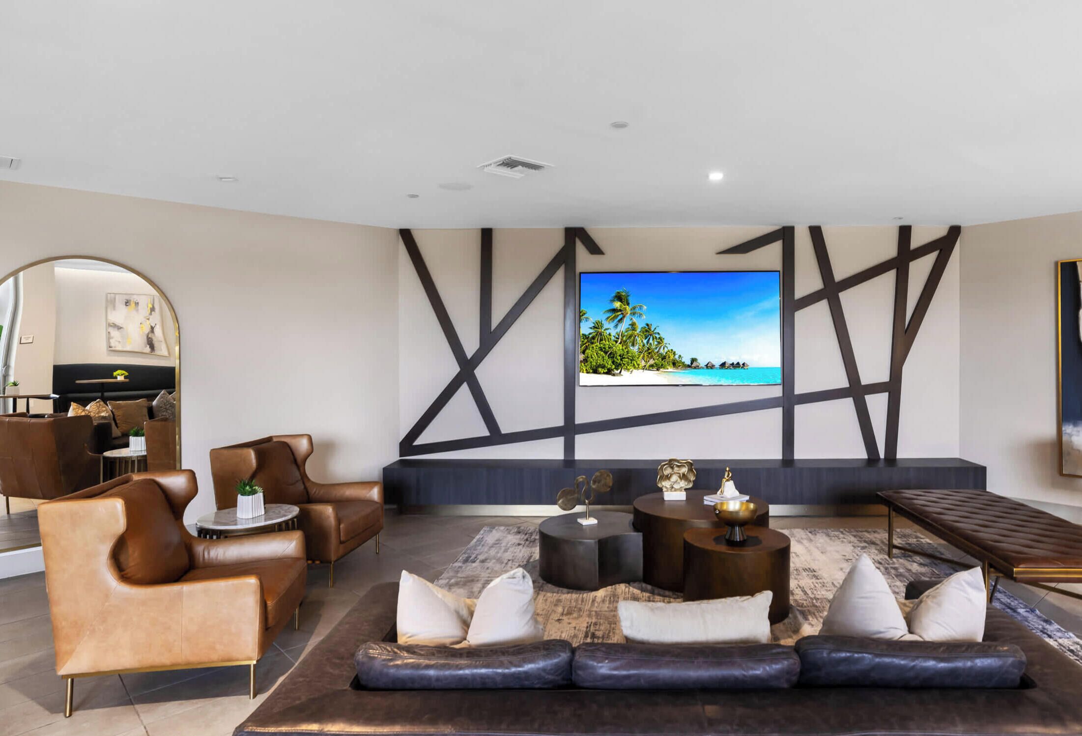 Una sala de estar moderna con un televisor de pantalla plana grande, sofás de cuero y una mesa de centro.