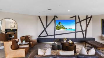 Una sala de estar moderna con un televisor de pantalla plana grande, sofás de cuero y una mesa de centro.