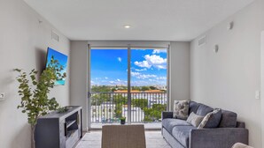 A modern living room with a grey sofa, a flat-screen TV, and a potted plant. - Sleek Miami 2BR | Free parking | Pool & Gym (Miami)