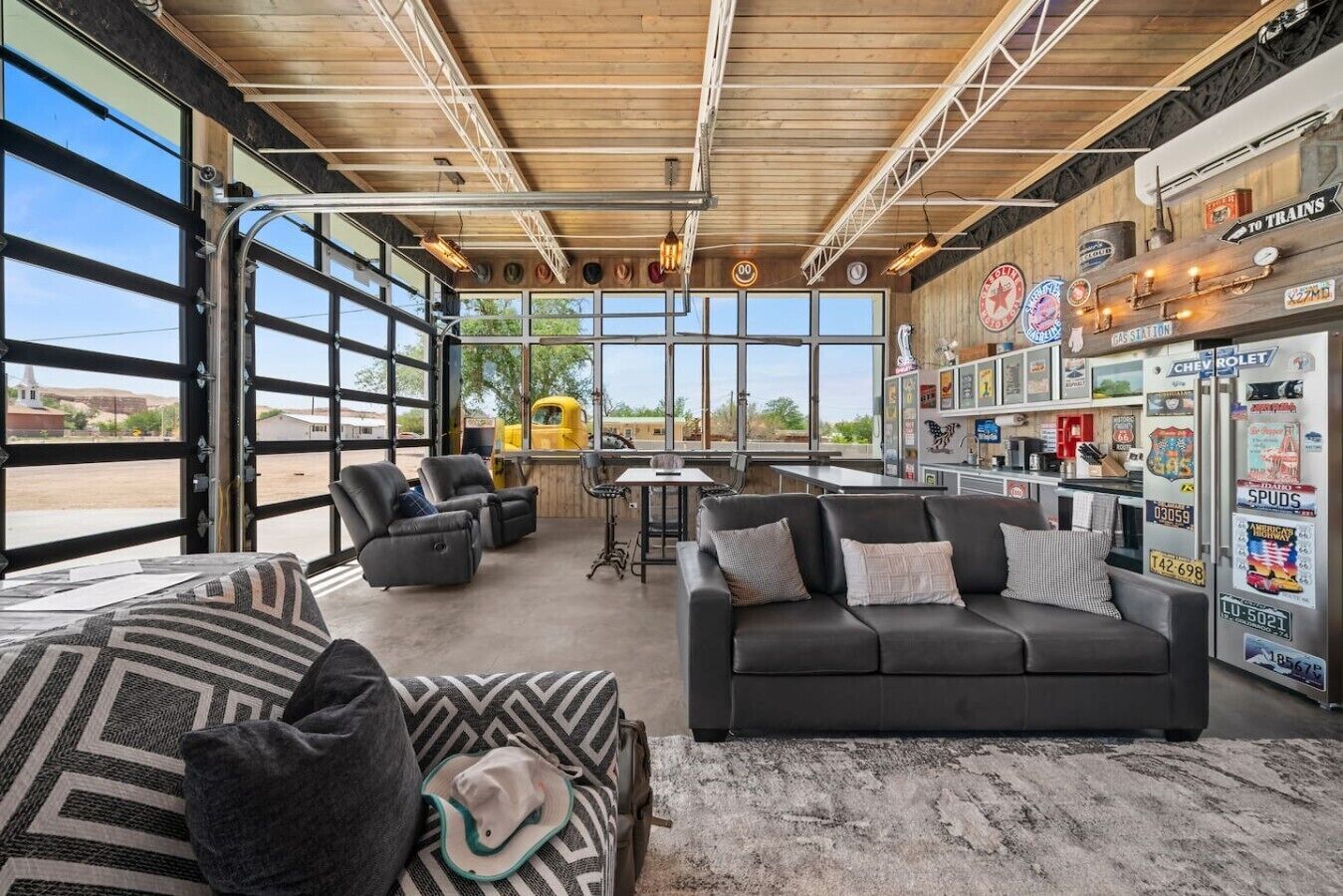 A modern interior with a black leather sofa, a dining table, and a large window overlooking a desert landscape.