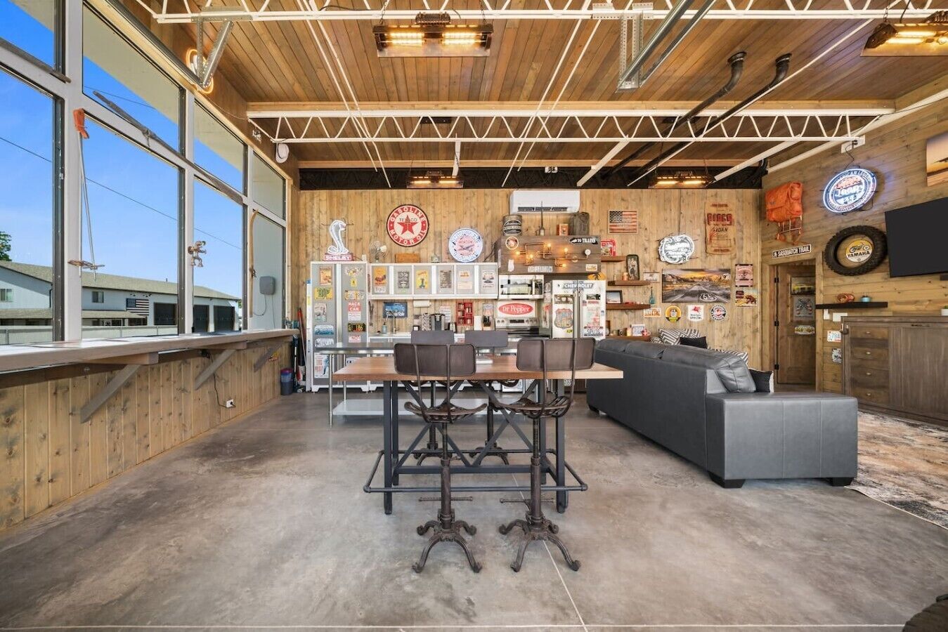 An interior with a wooden ceiling, a bar area, a seating area with a sofa and chairs, and various wall decorations.