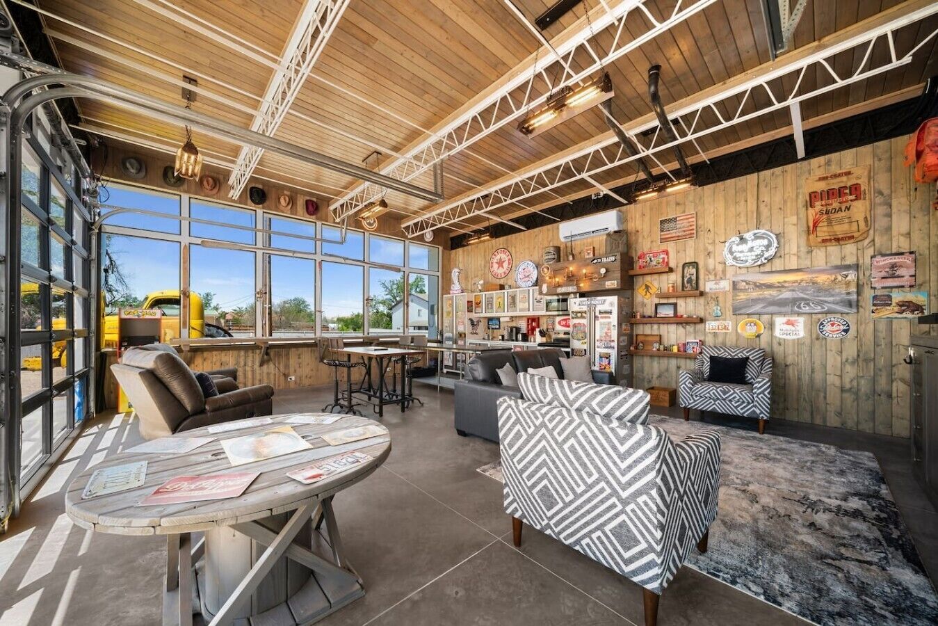 A rustic interior with a wooden ceiling, large windows, a bar area, and various memorabilia on the walls.