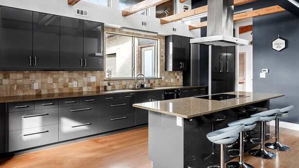 A modern kitchen with dark cabinets, a large island, and bar stools.