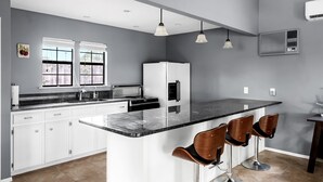 A kitchen with white cabinets, a marble countertop, and a central island with bar stools.
