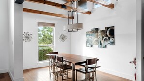 A dining area with a wooden table and chairs, a hanging light fixture, and abstract wall art.