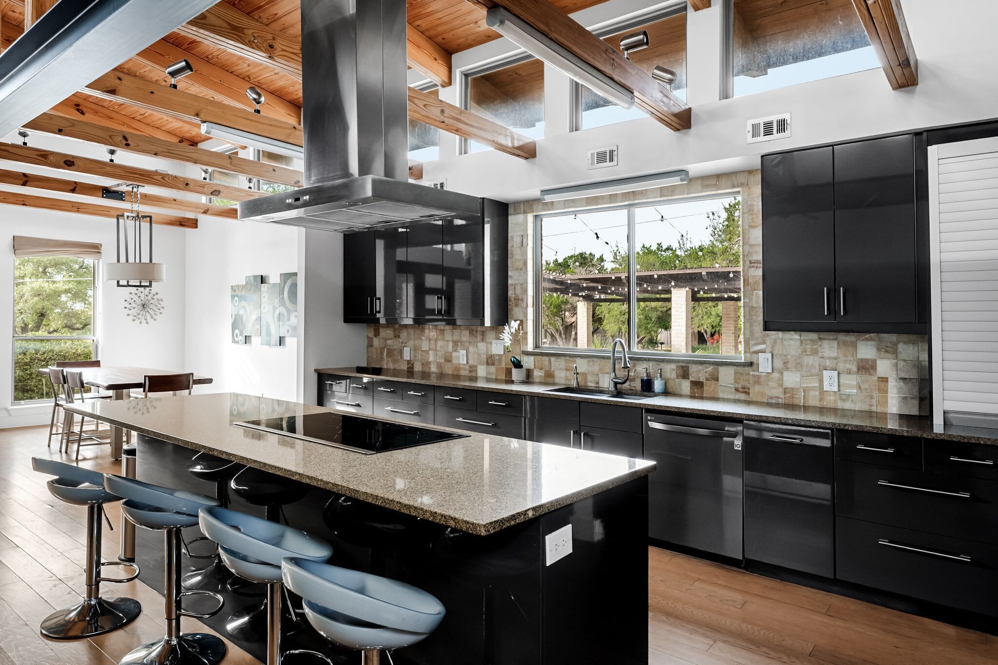 A modern kitchen with a large island, bar stools, and a view of the outdoors.