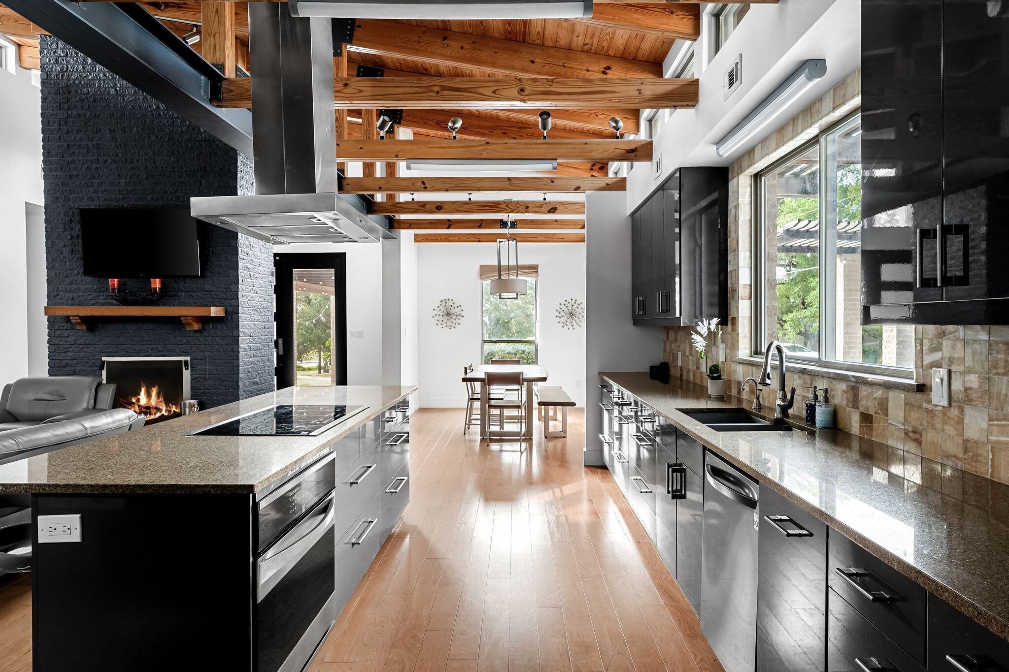 A modern kitchen with a central island, built-in appliances, and a dining area with a view.