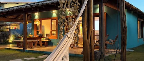 A hammock, wooden swing, and a building with a patio.