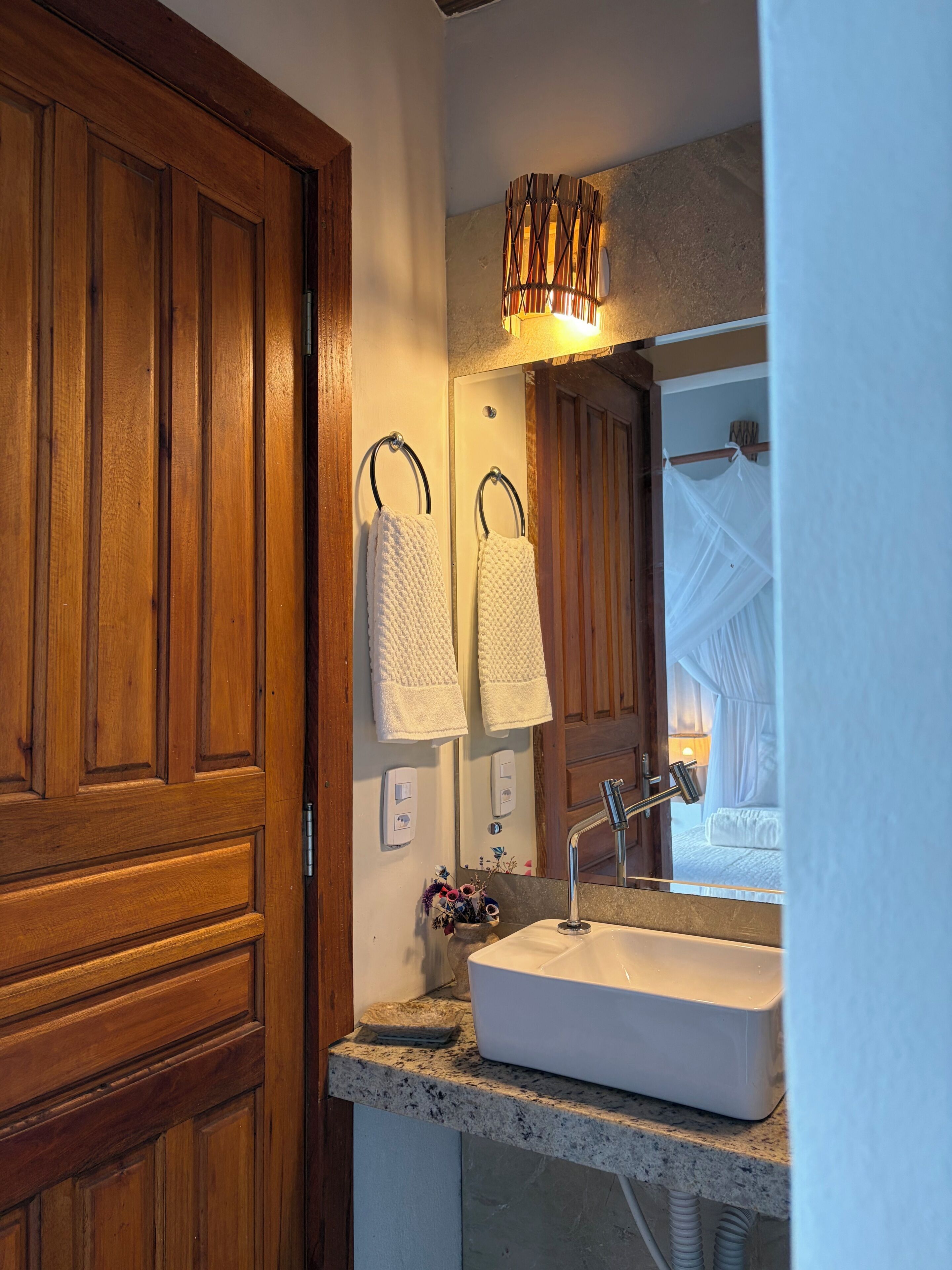 A bathroom with wooden cabinets, a white sink, a mirror, and a wall-mounted towel rack.