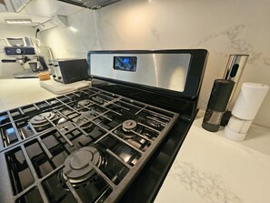 A kitchen with a stove, coffee maker, and salt and pepper shakers. - SJ City Oasis Pool Billiards Power & Water Back up (San Juan)
