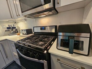 Une cuisine équipée d’une cuisinière à gaz, d’un four, d’un four à micro-ondes encastré et d’une machine à café.