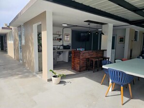 Un espace de vie ouvert comprenant un coin cuisine, une table à manger avec des chaises et une plante en pot.