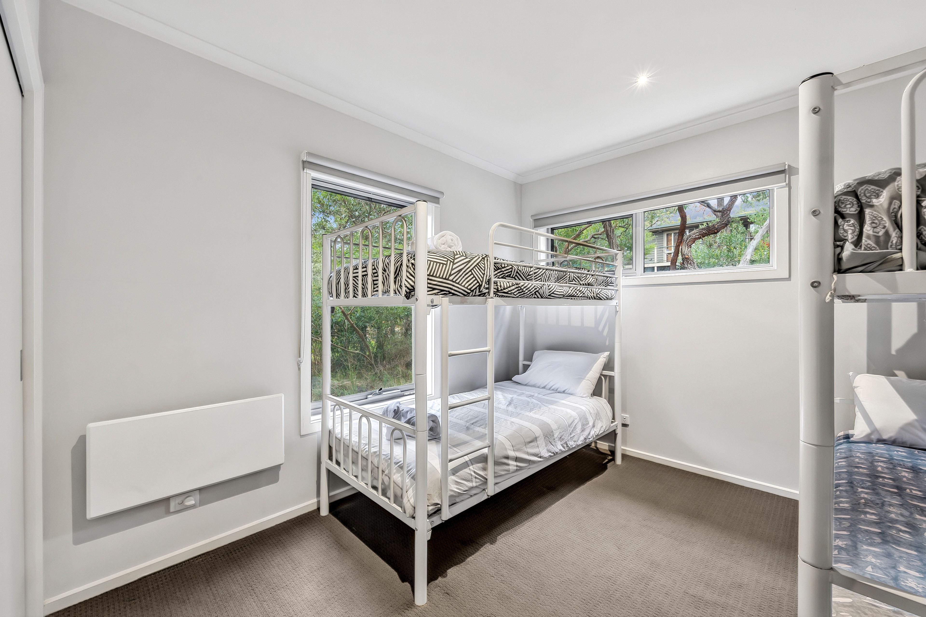 A bunk bed room with a window, a radiator, and a door.