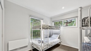 A bunk bed room with a window, a radiator, and a door. - Fairhaven Treetops Lookout (Fairhaven)