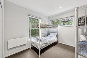 Ein Schlafzimmer mit Etagenbetten, einem Fenster, einer Heizung und einer Tür.