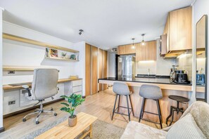 Eine moderne Küche mit Einbaukühlschrank, Holzschränken und einer Bar mit Sitzgelegenheiten.