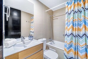 A modern bathroom with a shower, toilet, and sink. - Estoril Suite | Clínica y Centro Comercial (Las Condes)