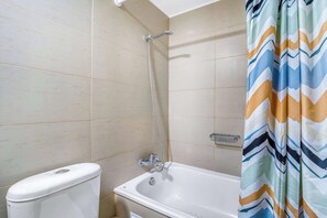 A bathroom with a toilet, a bathtub, and a shower. - Estoril Suite | Clínica y Centro Comercial (Las Condes)