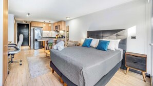 Un dormitorio moderno con una cama grande, un escritorio y una kitchenette.