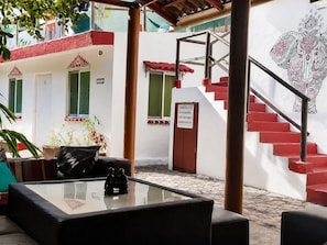 A courtyard with a glass table, red steps, and a white building with green windows.