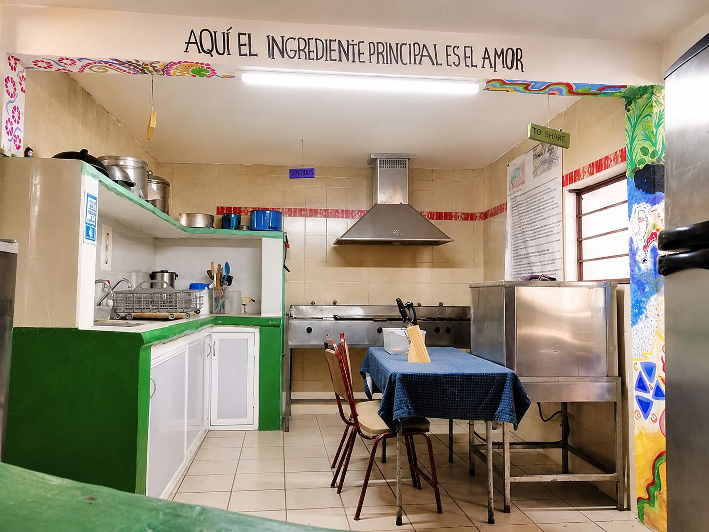 A kitchen with a blue table, white cabinets, and a stainless steel refrigerator.