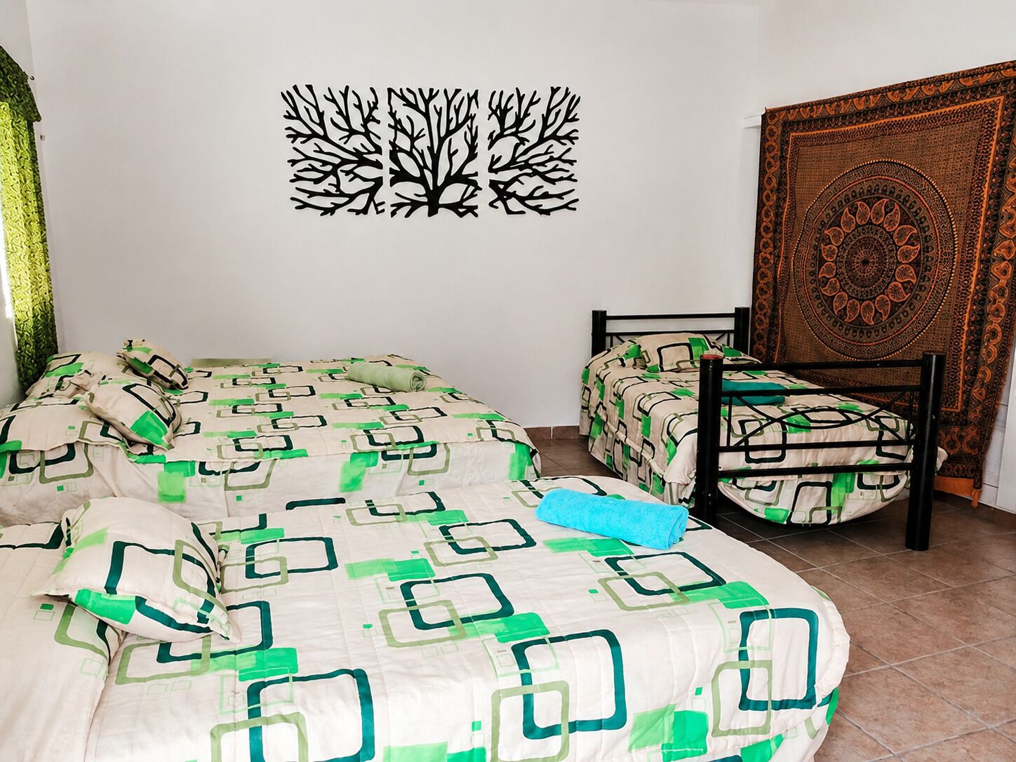 Un dormitorio con cama, una silla y un tapiz en la pared.