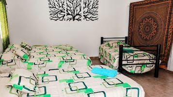 Un dormitorio con cama, una silla y un tapiz en la pared.