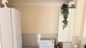 A compact kitchen with a refrigerator, stove, microwave, and a small sink. - Apartment Sleeps 6 With in Kilburn Lane (London)