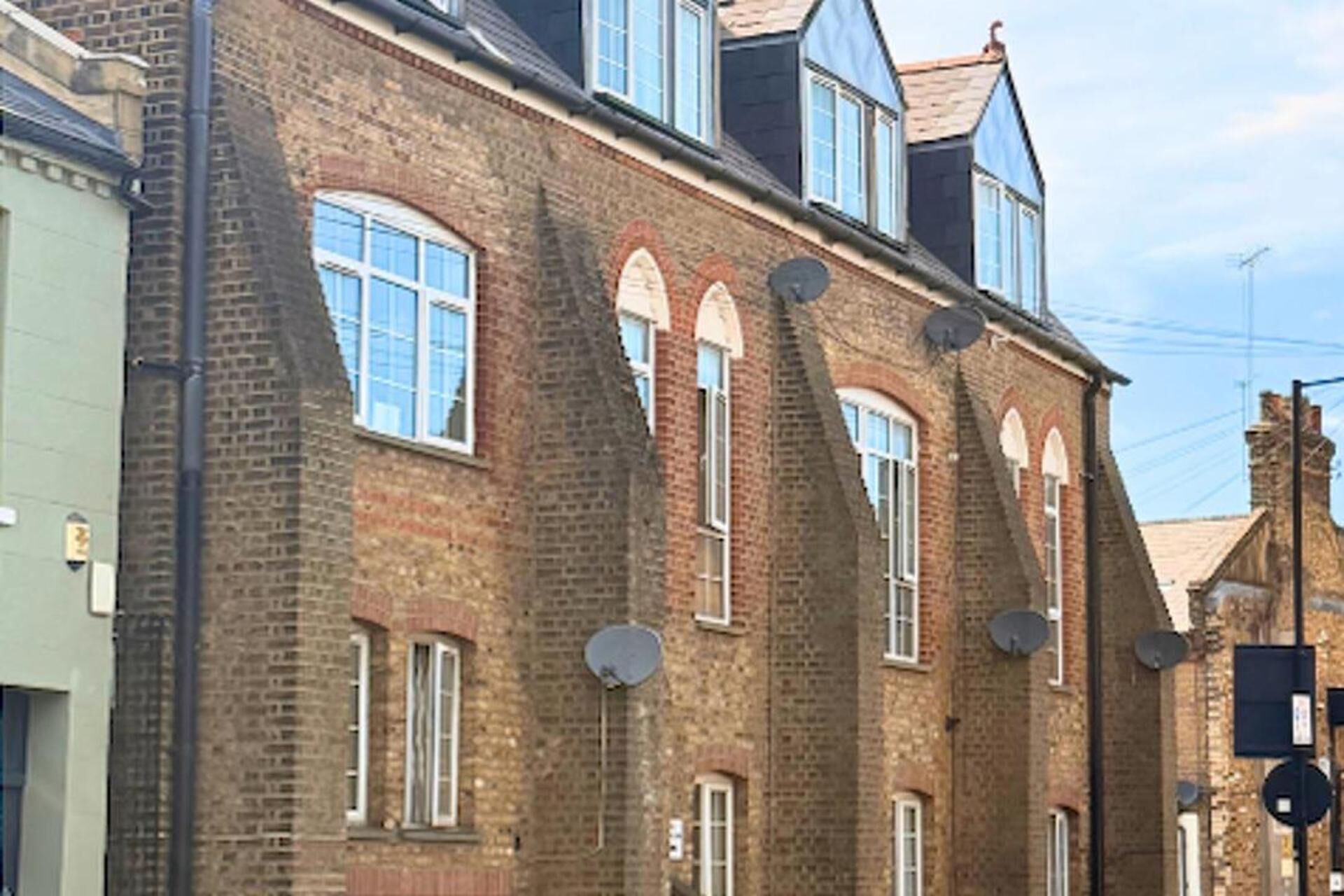 A multi-story brick building with arched windows and satellite dishes.