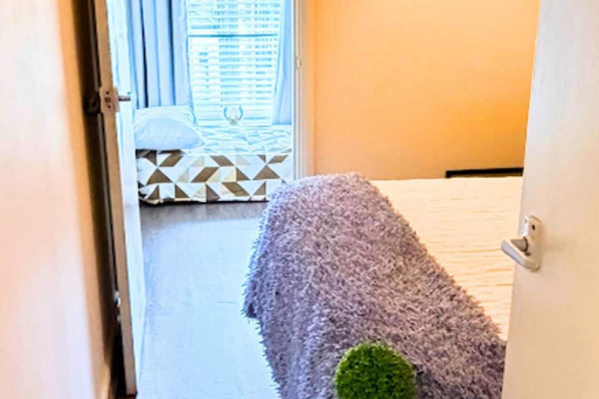 A room with a bed, a patterned rug, and a window with blinds.