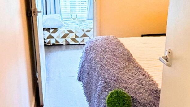 A room with a bed, a patterned rug, and a window with blinds. - Apartment Sleeps 6 With in Kilburn Lane (London)