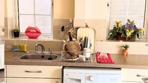 A kitchen with a washing machine, a sink, and various kitchen utensils. - Apartment Sleeps 6 With in Kilburn Lane (London)