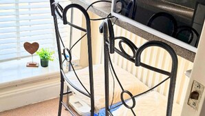 A metal-framed bunk bed with a built-in microwave above it, a window with blinds, and a small potted plant on the windowsill. - Apartment Sleeps 6 With in Kilburn Lane (London)