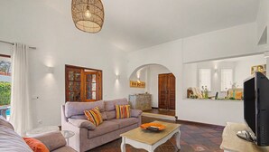 Un salon comprenant un canapé, une table basse, un téléviseur et un miroir décoratif.