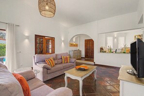 A living room with a sofa, a coffee table, a television, and a decorative mirror. - Villa Monte Galego. Private pool and garden. A space just for you. (Guia)