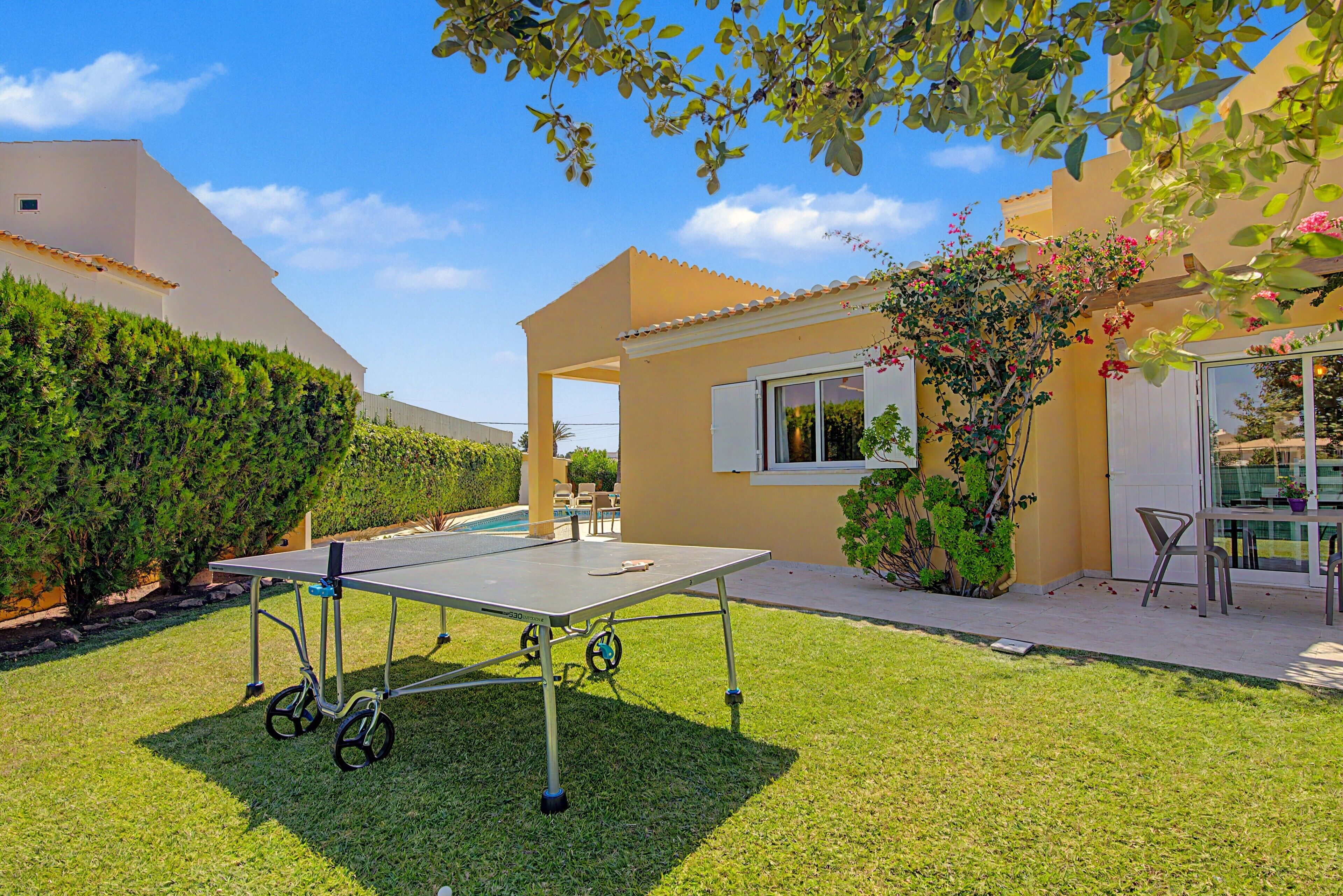 Ein gepflegter Außenbereich mit Tischtennisplatte, einem kleinen Garten und einer Terrasse mit Sitzmöbeln.
