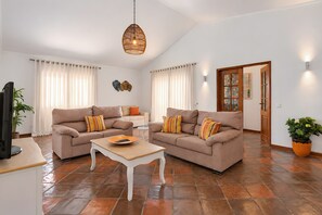 A living room with two sofas, a coffee table, a TV, and a decorative wall piece. - Villa Monte Galego. Private pool and garden. A space just for you. (Guia)