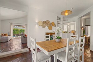 A dining area with a wooden table and white chairs, surrounded by white walls with decorative wall art. - Villa Monte Galego. Private pool and garden. A space just for you. (Guia)