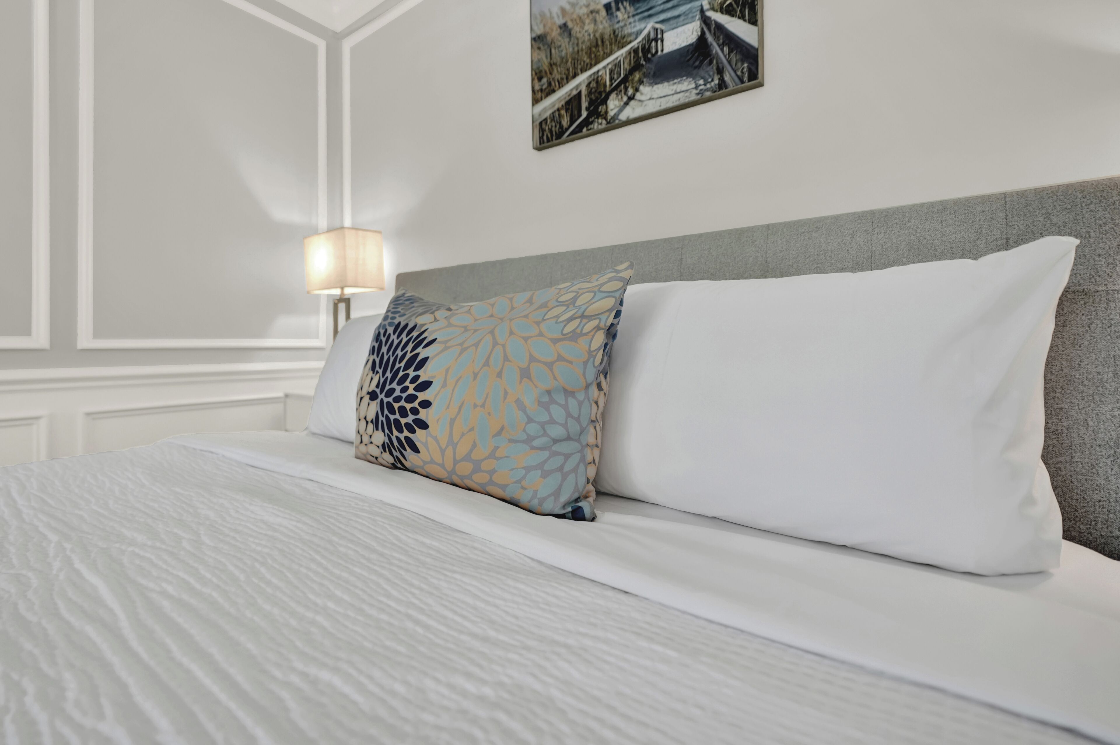 Una cama bien hecha con ropa de cama blanca y una almohada decorativa.
