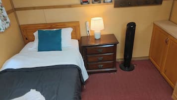 Une chambre d’hôtel comprenant un lit, une table de chevet avec une lampe, une commode et une étagère murale décorée de tableaux.