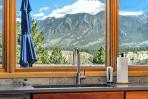 Una cocina con un lavabo, una ventana con vista a la montaña y una toalla colgada en la ventana.
