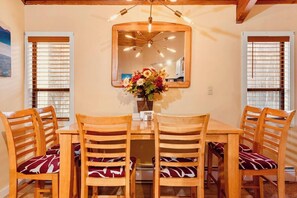 A dining area with a wooden table and chairs, a mirror above the table, and a vase with flowers. - Exposed Beam Getaway - Heart of NH White Mountains (Thornton)