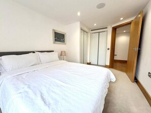 A bedroom with a large bed, a bedside lamp, a framed picture on the wall, and a door leading to a closet. - Luxury 4 Bedrooms in Jerome House London (London)