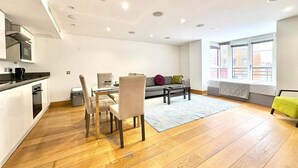 Een modern appartement met een eethoek, keuken en een groot raam met uitzicht op de stad.