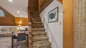 Eine Holztreppe führt zu einer erhöhten Ebene, einem Essbereich mit Tisch und Stühlen sowie einer an der Wand hängenden Karte.