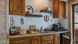 Eine Küche mit Holzausstattung, Spüle, Kaffeemaschine und diversen Küchenutensilien.